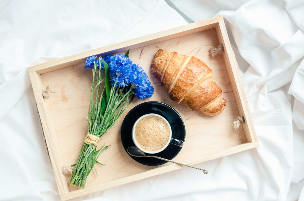 Korenbloem op een ontbijtbord naast een croissant en koffie