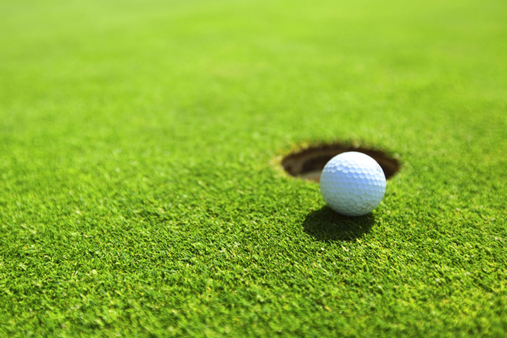 Golfgras met hole en golfbal
