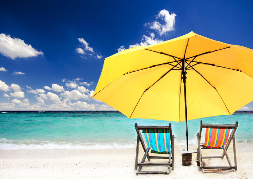 Strandidyll: zwei Liegen unter einem gelbem Sonnenschirm